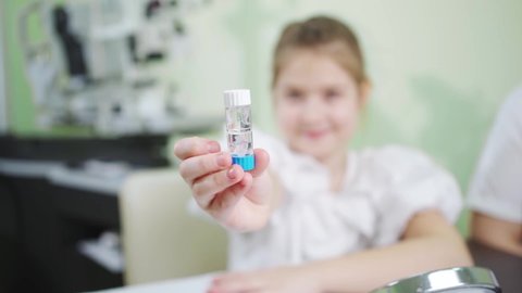 the girl is holding a case with orthokeratological contact lenses. a modern method of correction of myopia and astigmatism. contact night lenses for sleep. advertising of the ophthalmological clinic.