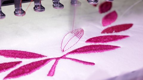 Embroidery design. Machine embroidery on a white towel with pink thread. 4k video Close up.