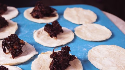 Women's hands are sculpting gomentashi cookies for the Purim holiday with poppy seeds.