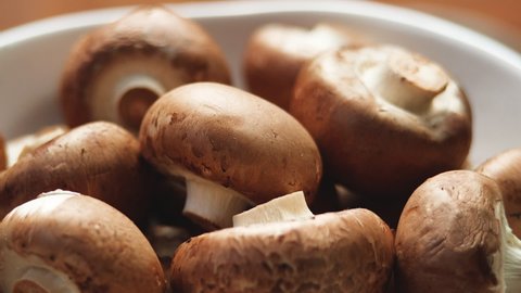 Side View Of Uncooked Fresh Raw Royal Champignon Mushrooms Rotating Close Up. Appetizing Brown Mushrooms Ready For Eating. Bowl with Edible Vegetables Cultivated Conception