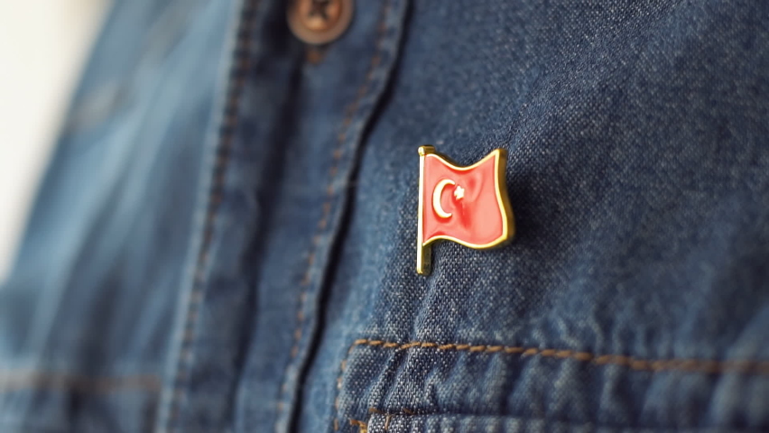 Turkish flag icon is pinned on blue jeans jacket. Turkey patriotism concept. Republic Day Holiday in Turkey. | Shutterstock HD Video #1087859083