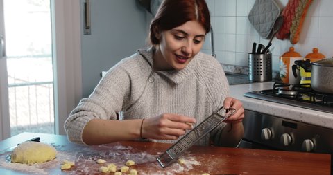 Young girl is stamping homemade little gnocchi on the kitchen table