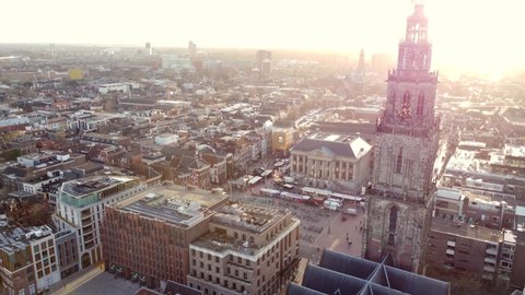 GRONINGEN, NETHERLANDS - 27. FEBRUARY 2022: Ascending aerial view above Grote markt and Martinitoren during sunset.