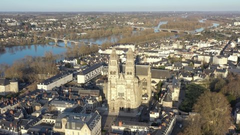 France, Tours city, Saint-Gatien cathedral during sunset (or sunrise) with Loire river in back. Long backward drone aerial view.