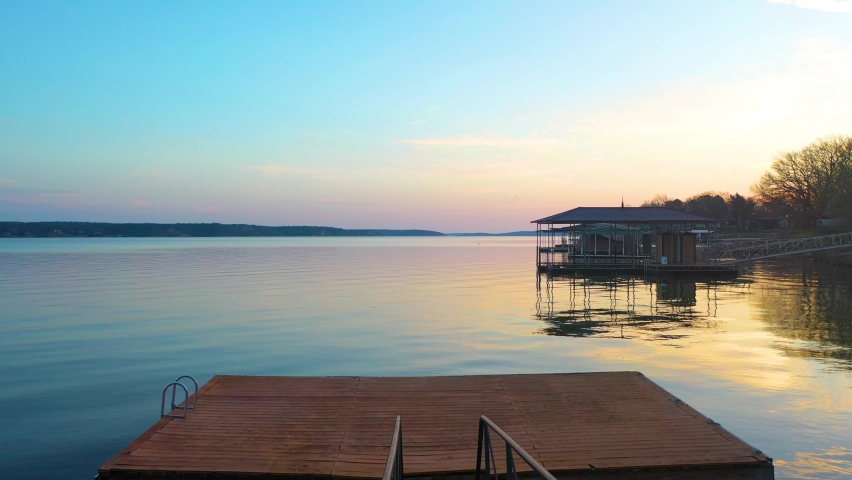 Empty Boat Dock On The Lake For Waterfront Home In Midwest Oklahoma With Beautiful Sunrise in Background. Aerial drone pullback reveal