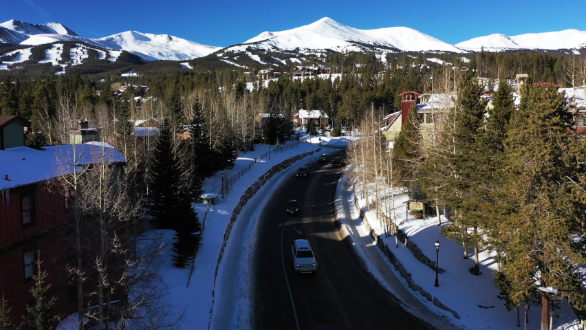 Aerial forward view of a mountain road with passing cars and snow capped mountains. Denver, Colorado. USA