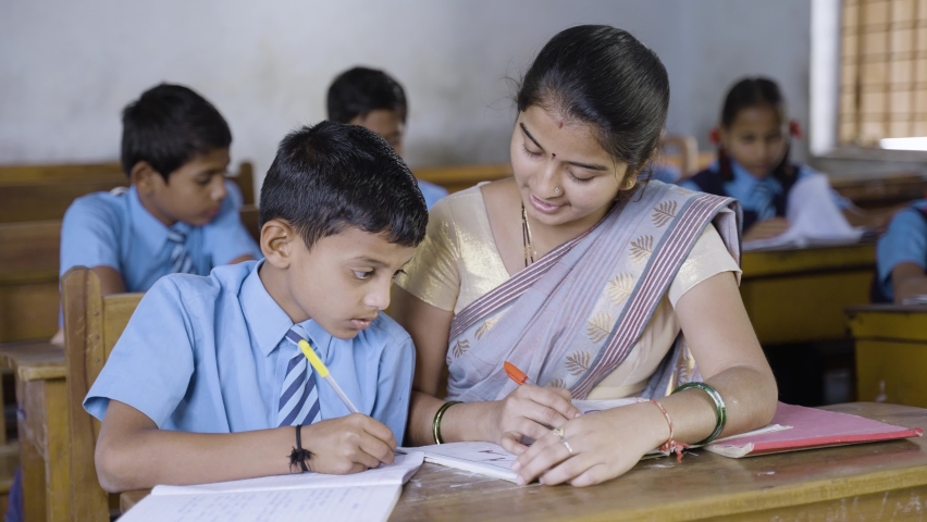 Teacher in classroom helping kid for studying at desk - concept of personal care, mentorship and coaching | Shutterstock HD Video #1087867493