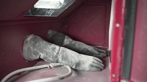 Praha , Česká republika , Czech Republic - 02 25 2022: Worker putting on gloves in a cabinet for sandblasting, slow motion.