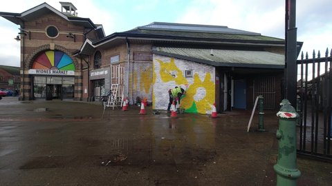 Widnes , United Kingdom (UK) - 02 23 2022: Artist Paul Curtis painting jungle tiger graffiti mural on Widnes town market building February 2022
