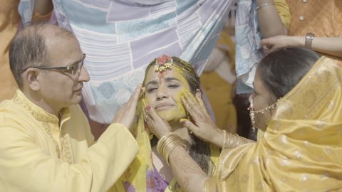 Dehradun, Uttarakhand India February 21, 2022-Turmeric is being applied to the bride in India called as Haldi Ceremony. An Indian wedding tradition. Haldi ceremony in a fun way. Indian people wearing