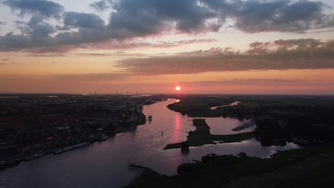 Kampen city skyline aerial view from the river IJssel with the sunset in the distance during a cold winter evening.
