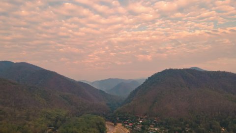 Aerial view motion Time-lapse of Altocumulus clouds over the silhouette mountains amid the smoke from the forest fires in summer at Mae Hong Son province Northern Thailand.