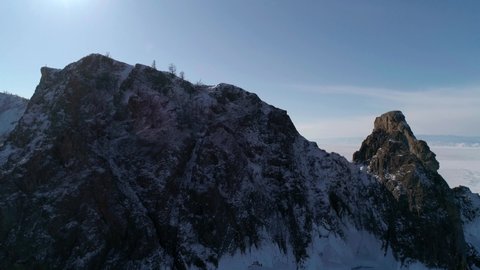 Aerial view of cape Khoboy, Olkhon island. Tall rocks in frozen lake Baikal with people walking around. Popular touristic destination. Winter landscape. Panoramic view