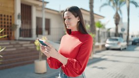 Young woman smiling confident watching video on smartphone at street
