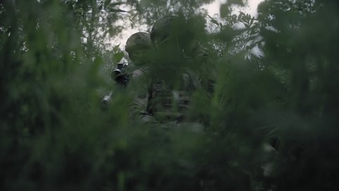 Soldiers in ambush in a dense forest with a sniper rangefinder and a sniper rifle. Special Forces soldiers work as a team. Soldiers in full gear. No war