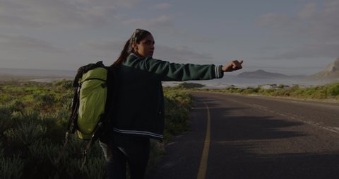 Animation of biracial woman walking on road, trying to hitch-hiking. travel, holidays and freedom concept digitally generated video.