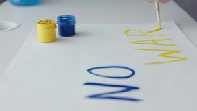 no war words painting in yellow blue colors art painting paintbrush paint on white paper. attack military operation concept Ukraine conflict, no war sign writings, no war text letters - Powered by Shutterstock - Get 15% off with code: PIKWIZARD15