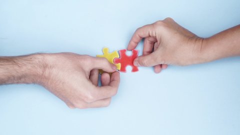 international autism awareness day - hands ot two people holding and connecting jigsaw puzzles