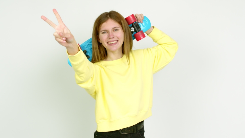 Young woman holding roller skates and celebrating a victory over isolated background