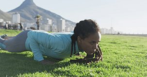 Animation of rugby ball icons over biracial woman exercising in park. health and fitness concept digitally generated video.