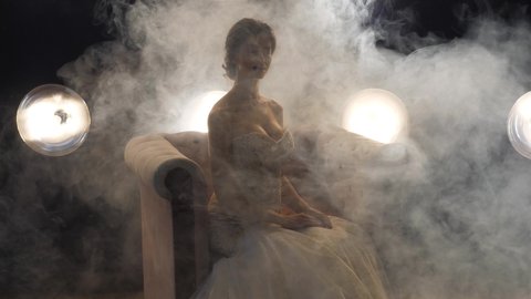Fiancee in dress poses in smoke for wedding photoshoot