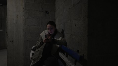 Young people are scrolling war news feed while hiding in a basement, russian invasion