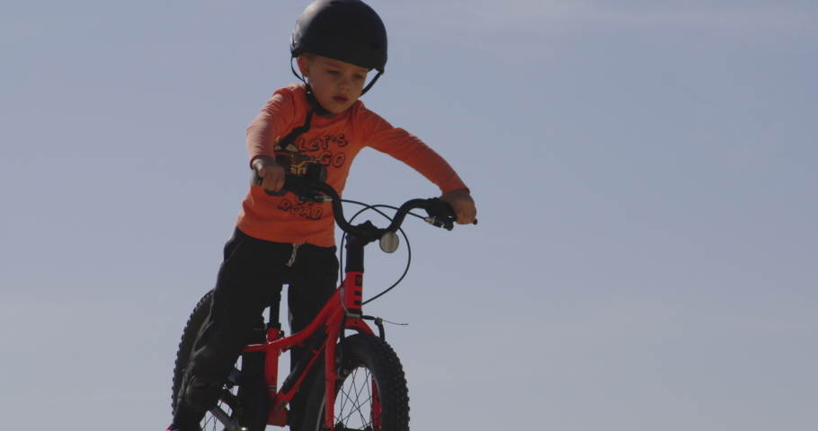 Young boy rides bicycle down steep, dusty hill and crashes. Crying to mother. Slow motion, static shot. Royalty-Free Stock Footage #1087898111