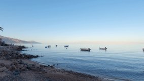 Boats moored on shore of Dahab city at sunset, Egypt. Sky for copy space
