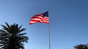 American Flag blowing in the wind with a blue sky background. USA American Flag. Waving United states of America famous flag in front of blue sky - American concept. Loop ready in 4k resolution.