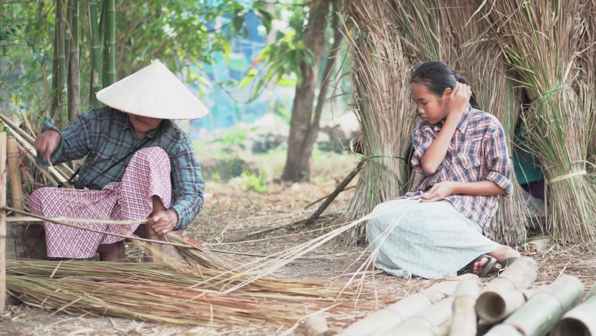 Grandmother and her granddaughter were fabricated leaf roof. 
Show their smile , that mean's the good relation between them. 
Rural people  life in side-country of south east asia. Royalty-Free Stock Footage #1087901107