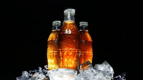 Glass wet soda old bottles in ice cubes rotate in a circle on an isolated black background in the rays of light. 4k slow motion video with speed ramp effect.