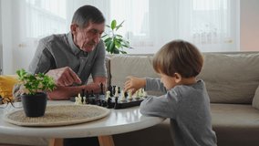Senior teacher learning a 4 year old child playing chess, sitting at the table - Powered by Shutterstock - Get 15% off with code: PIKWIZARD15