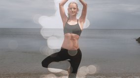 Animation of light spots over caucasian woman practicing yoga at beach. world meditation day and celebration concept digitally generated video.
