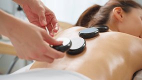 Asian young relaxing woman getting back massage therapy with hot stone. Attractive beautiful girl lying on massage table, getting physiotherapy from masseuse for skin and body care in spa beauty salon - Powered by Shutterstock - Get 15% off with code: PIKWIZARD15