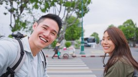 POV Asian couple backpacker use mobile phone take a video clip in city. Attractive man and woman tourist traveler travel on street, using smartphone record vlog on holiday vacation trip in Thailand.