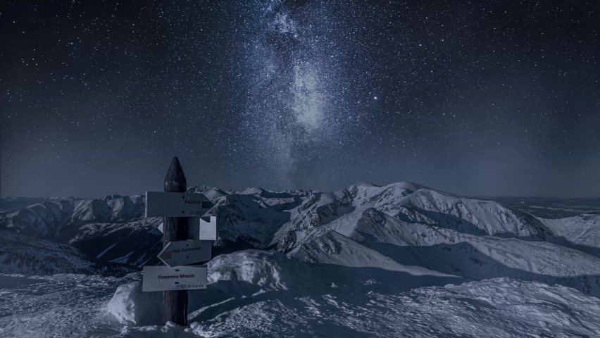Timelapse of miky way over mountain Kasprowy Wierch in winter. Night hiking in Tatras.