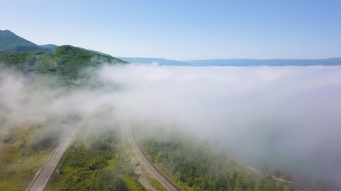 Flying above the clouds. Coast of Lake Baikal. Mountains covered with forest. Russia, Aerial View Hyperlapse