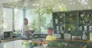 Animation of leaves over happy african american father and son cooking together. family, togetherness, spending quality time concept digitally generated video.