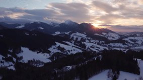 Aerial view sunset over winter mountain trees landscape, colored clouds at dusk. 4K stock video. 