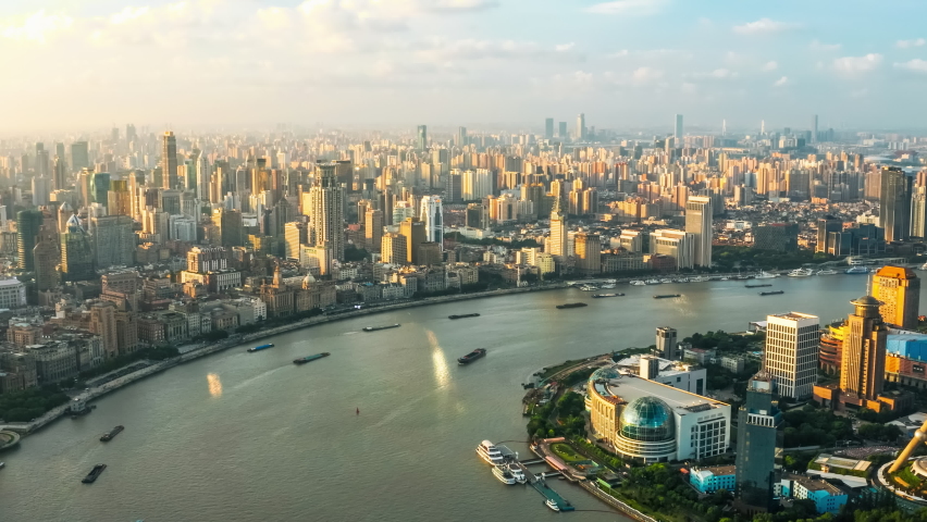 Aerial footage of river and city skyline with buildings in Shanghai at sunset, China.