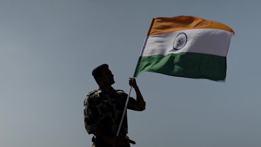 silhouette of Indian army soldier holding waving Indian flag on top of mountain - concept of independence or repubilc day celebration, patriotism and pride Royalty-Free Stock Footage #1087915873