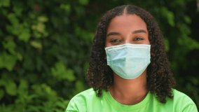 Panning shot of beautiful bi racial African American girl  teenager young woman outside wearing a face mask during COVID-19 Coronavirus pandemic - Powered by Shutterstock - Get 15% off with code: PIKWIZARD15