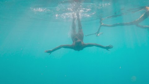Slow motion: Woman diving underwater in pristine clear water cenote in Mexico. Female swimming underwater in blue lagoon enjoying tropical vacations 