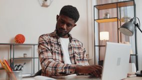 African american man freelancer using laptop computer sitting at desk working from home office. Adult guy businessman e-learning, browsing internet, online shopping, remote job on pc in living room