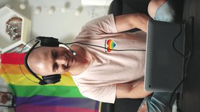 Bald caucasian gay gamer playing computer games on his laptop while sitting on a black sofa. Vertical indoor shot. . High quality 4k footage