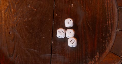 Pirate plays craps game throwing white marked cube-shaped dice on patterned wooden barrel top IN cabin of pirates ship closeup