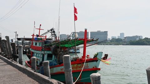 Pattaya , Chonburi , Thailand - 12 03 2021: A boat with a red flag docked and Pattaya City is at the background, Pattaya Fishing Dock, Chonburi, Thailand.