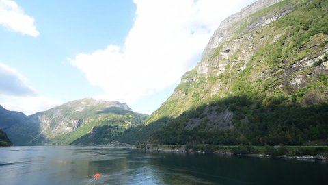Unique, amazing time-lapse footage where the camera is placed in the front of a cruise ship, that is docked at the most famous fjord of Norway, Geirangerfjord. Cloud shadows are dancing on the hills.