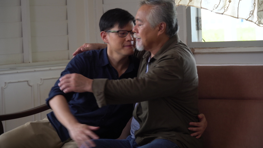 asian  senior old father sitting on sofa comforting and hugging adult  son  at home Royalty-Free Stock Footage #1087929761