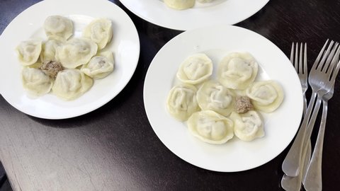 Homemade and handmade pelmeni. Russian national cuisine. It made from dough and beef meat with onion inside. Delicios healthy food. On the brown solid wood table with rolling pin. Metal forks 